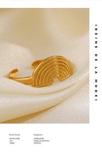 Close-up of gold geometric half-circle ring with rainbow relief on champagne silk