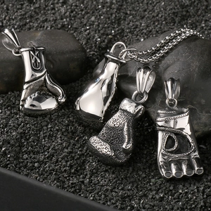Vue macro de pendentifs gants de boxe et pieds en argent poli sur des pierres sombres