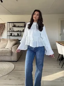 Detail of white bohemian chiffon blouse featuring layered ruffles and flared sleeves