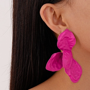 Close-up of vibrant magenta pleated petal earrings with a matte finish on a model