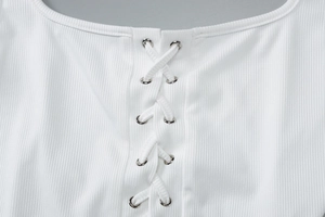 Close-up of white ribbed knit fabric with metal eyelets and cross lace-up detail on top