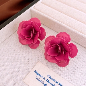 Vue macro de boucles d'oreilles roses 3D avec finition mate sur boîte en velours beige