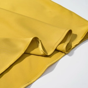 Detail of yellow satin fabric showing high-quality hem stitching and silky texture