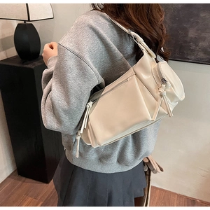 Détail du sac à bandoulière plissé crème avec de longs glands en cuir et une texture PU souple