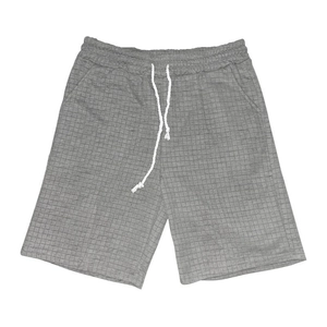 Detail of grey waffle knit men's casual shorts with white drawstring on plain background