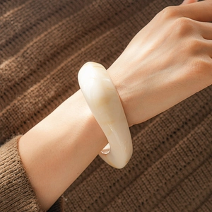 Detail of chunky cream resin cuff bracelet on brown knit sleeve for chic autumn style