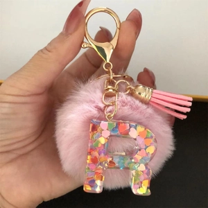 Detail of pink pompom and resin letter R keychain with colorful heart glitter