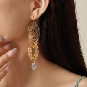 Close-up of gold hollow multilayer earrings with crystal pendant on model's ear