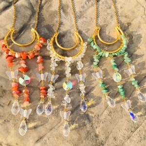 Three celestial sun catchers with crystal stones and golden moon charms on a rock surface