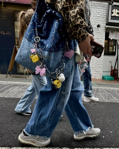 Close-up of colorful heart and duck charms attached to a blue denim handbag