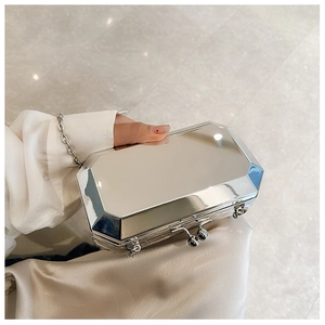 Silver geometric evening clutch with mirror finish held by hand featuring chain strap