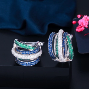 Macro detail of triple-layered hoop earrings with green, blue, and clear zircon stones