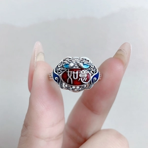 Detail of silver Ruyi ring with red and blue enamel clouds in a handheld close-up