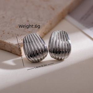 Detailed view of oval metal earrings with vertical texture and silver polished finish