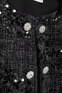 Details einer schwarzen Tweedjacke mit glänzenden Pailletten und Strassknöpfen