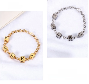 Detail of Lucky letter cubes on gold and silver titanium steel link bracelets