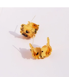 Detailed close-up of golden irregular textured C-shape earrings with black zircon stones