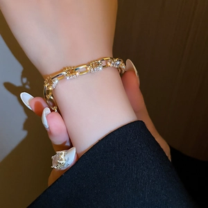 Nahaufnahme eines eleganten Gold-Zirkon-Kettenarmbands am Handgelenk bei warmem Licht