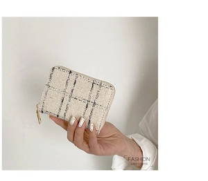 Close-up of hand holding a tweed zip-around wallet with black and white plaid pattern