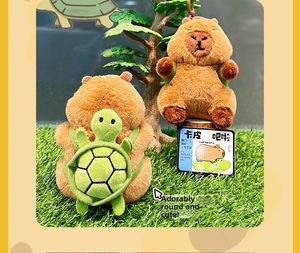 Close-up of cute plush capybara keychains with green turtle shell on grass background