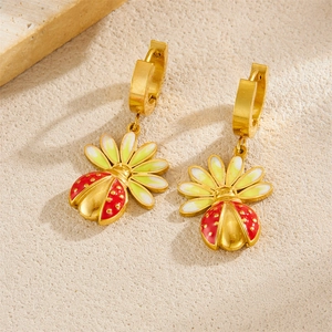 Détail de boucles d'oreilles coccinelle dorées avec émail rouge et ailes vert clair