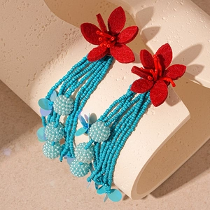 Detail of red fabric flower and blue bead tassels on long statement earrings