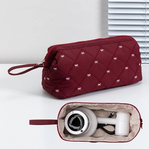 Macro view of burgundy quilted organizer with white bows for hairdryer and toiletries