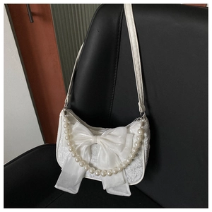Detail of white lace handbag featuring a large silk bow and elegant pearl handle