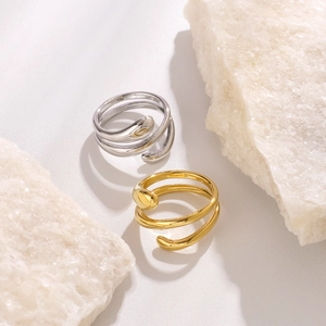 Minimalist fluid stainless steel rings in gold and silver on white mineral stone