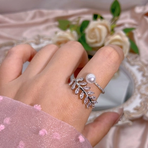 Elegant adjustable pearl leaf ring with marquise zircon stones on a pink silk background