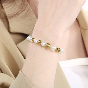 Bracelet perlé élégant avec perles blanches et billes dorées sur un poignet féminin