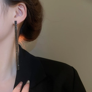 Nahaufnahme eleganter langer schwarzer Strass-Fransenohrringe an einem Model bei Licht