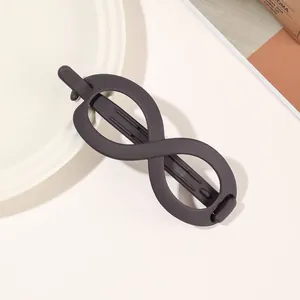 Detail of a matte dark brown infinity-shaped banana hair clip on a minimalist tray