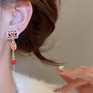 Détail de boucles d'oreilles lion chinois avec perles rouges et pompons dorés Nafu