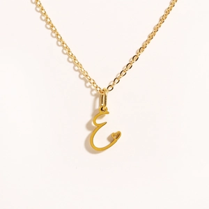 Detailed close-up of gold stainless steel necklace with capital letter E and heart cutout