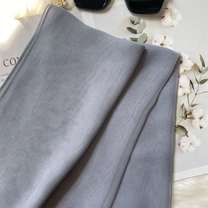 Close-up of light grey chiffon silk scarf texture with soft natural cotton background