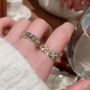 Detailed macro of gold plated enamel flower rings with zircon accents on finger