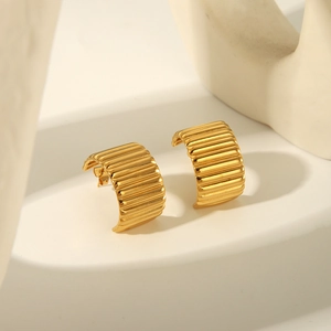 Vue détaillée de boucles d'oreilles dorées en C avec texture métallique plissée