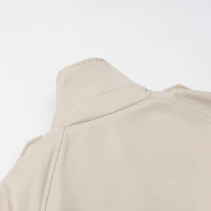 Détail du col montant et des coutures d'épaule sur un trench-coat court beige