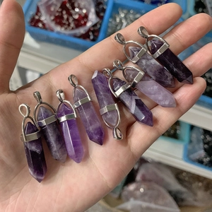 Macro shot of nine natural purple amethyst hexagonal prisms with silver metal clasps on hand