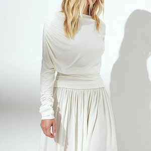 Detail of white long sleeve off-shoulder top with elegant draped folds and soft texture