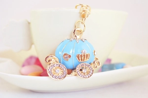 Detail view of a gold pumpkin carriage keychain with blue enamel and sparkling rhinestones