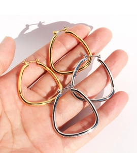 Detailed view of geometric water drop earrings in polished gold and silver finishes