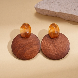 Boucles d'oreilles rondes géométriques en bois et résine ambre sur fond de pierre