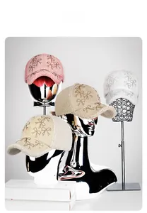 Detail of plush baseball caps with bow designs on metallic mannequins in four soft colors