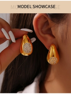 Détail macro de boucles d'oreilles goutte dorées avec zircons blancs sur modèle