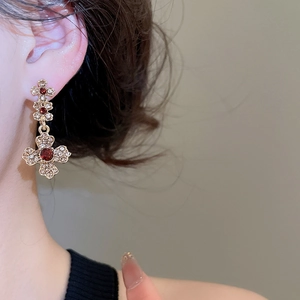 Close-up of vintage flower cross earrings with red crystals on a female model