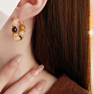 Vintage gold plated hoop earrings with natural tiger eye stones worn by a model