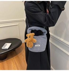Detailed close-up of a blue faux shearling bucket bag with a cute brown bear charm