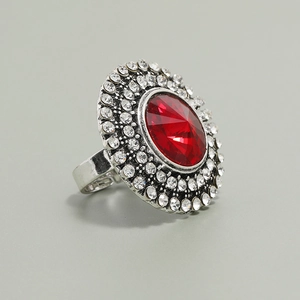 Close-up of vintage silver ring featuring a large oval red stone and white rhinestones